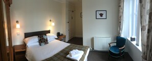 A hotel room with a bed, bedside tables, a chair, a radiator, and a window with curtains. - Loch Shiel Hotel (Acharacle)