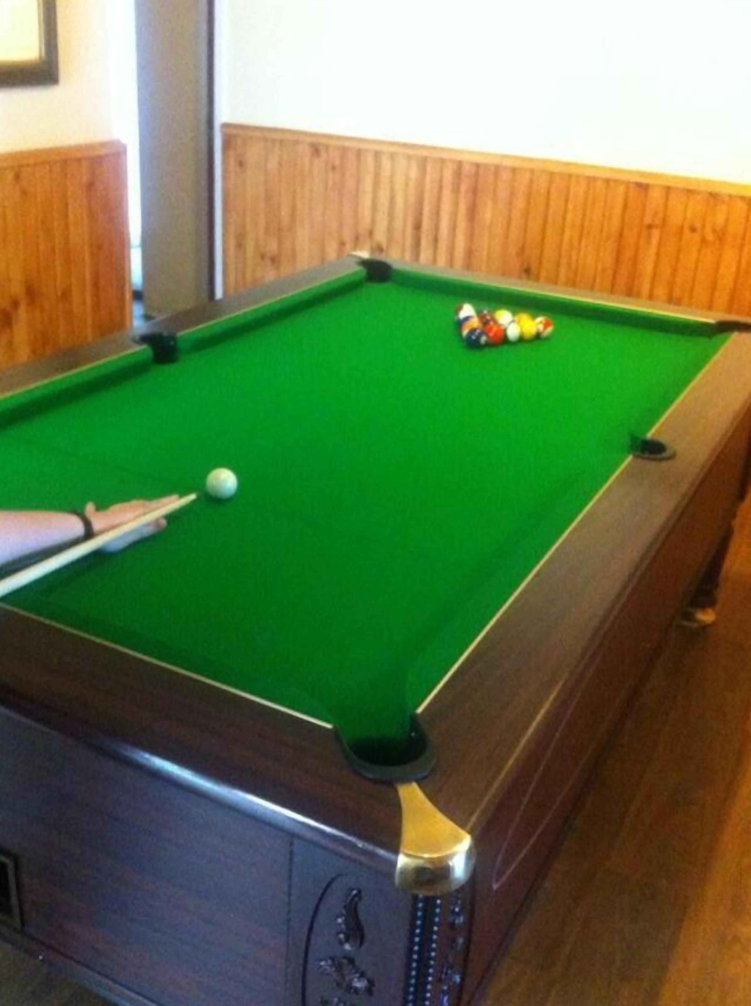 A pool table with balls and a cue stick.