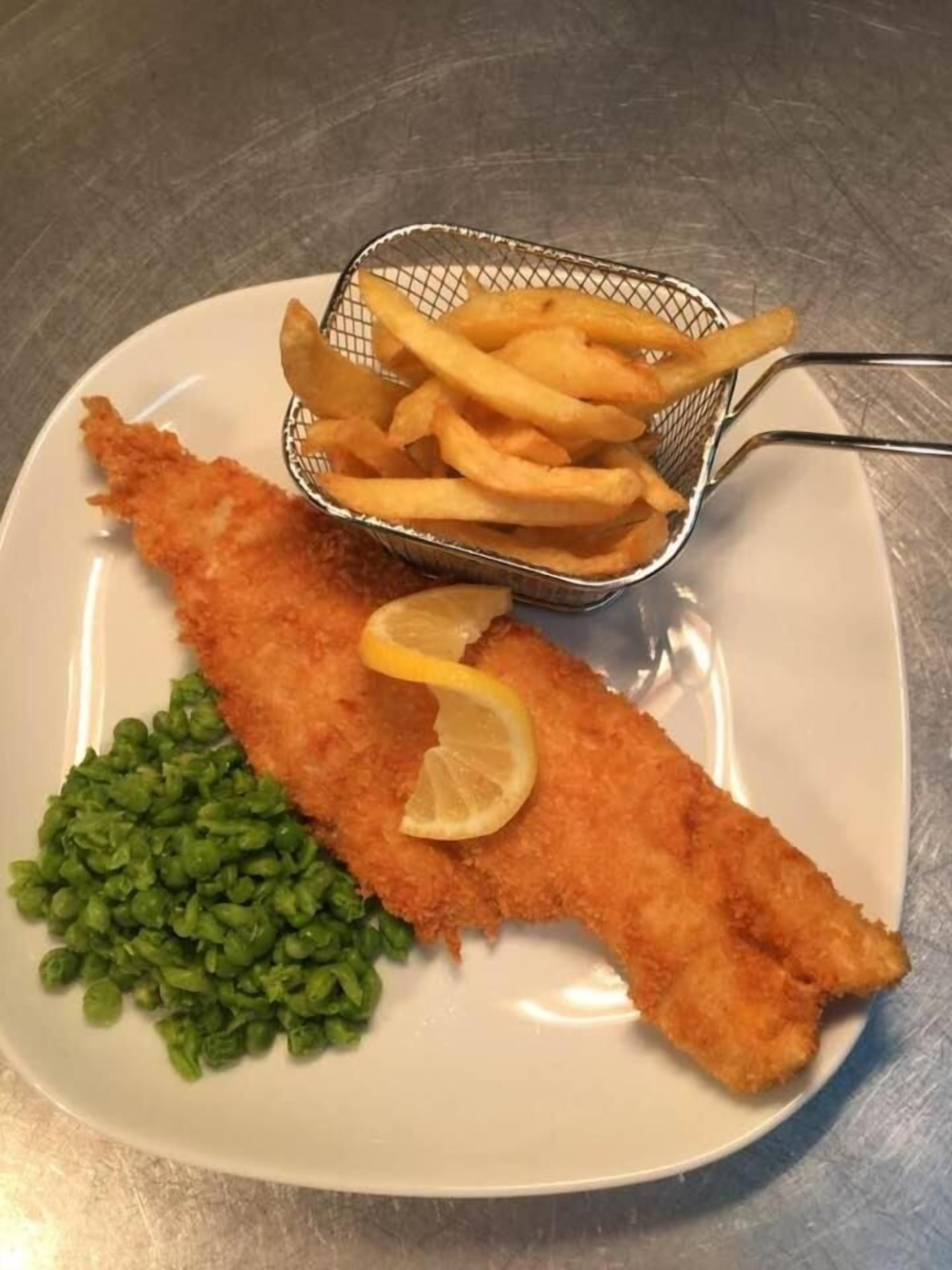 Un plato con un filete de pescado empanizado, papas fritas y guisantes verdes.