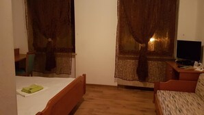 A room with a bed, a sofa, a TV, and curtains. - Gasthaus Lamm (Pforzheim)