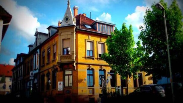 A yellow building with a balcony and a weather vane. - Gasthaus Lamm (Pforzheim)