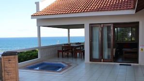 Ein überdachter Außenbereich mit Pool, Sitzgelegenheiten und Blick auf den Ozean.
