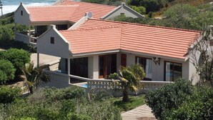 Ein Küstenhaus mit rotem Ziegeldach, einem Swimmingpool und Blick auf den Ozean.