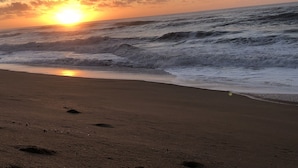 Ein Strand mit Wellen und einem Sonnenuntergang.