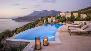 A private pool with a view of the sea and mountains, surrounded by lounge chairs and candles. - Ariá Estate Suites & Spa (East Mani)