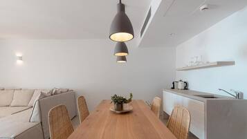 Un comedor moderno con una mesa de madera, sillas de mimbre y una lámpara colgante.