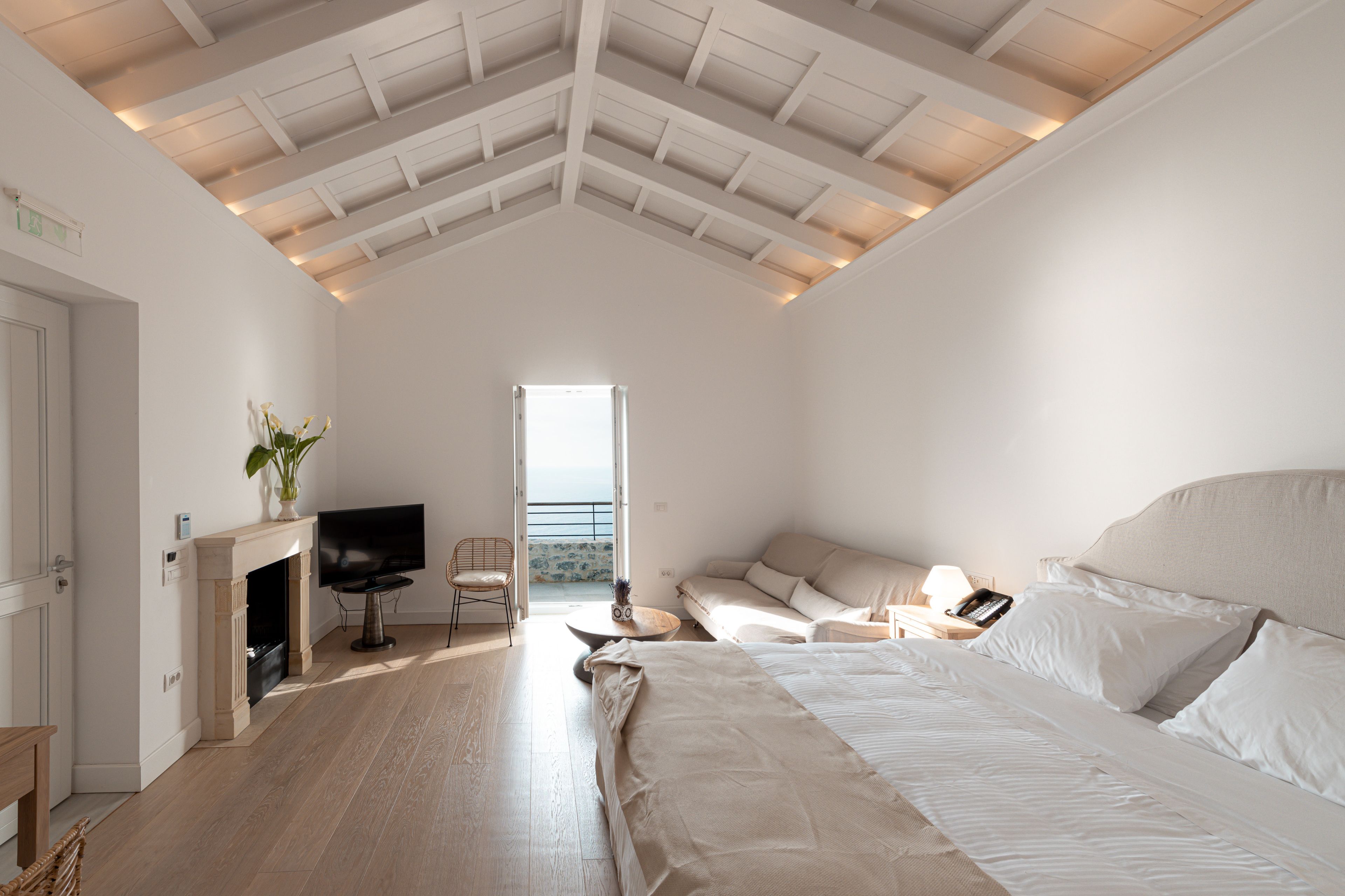 Un dormitorio espacioso con una cama grande, televisión, chimenea y vistas al balcón.