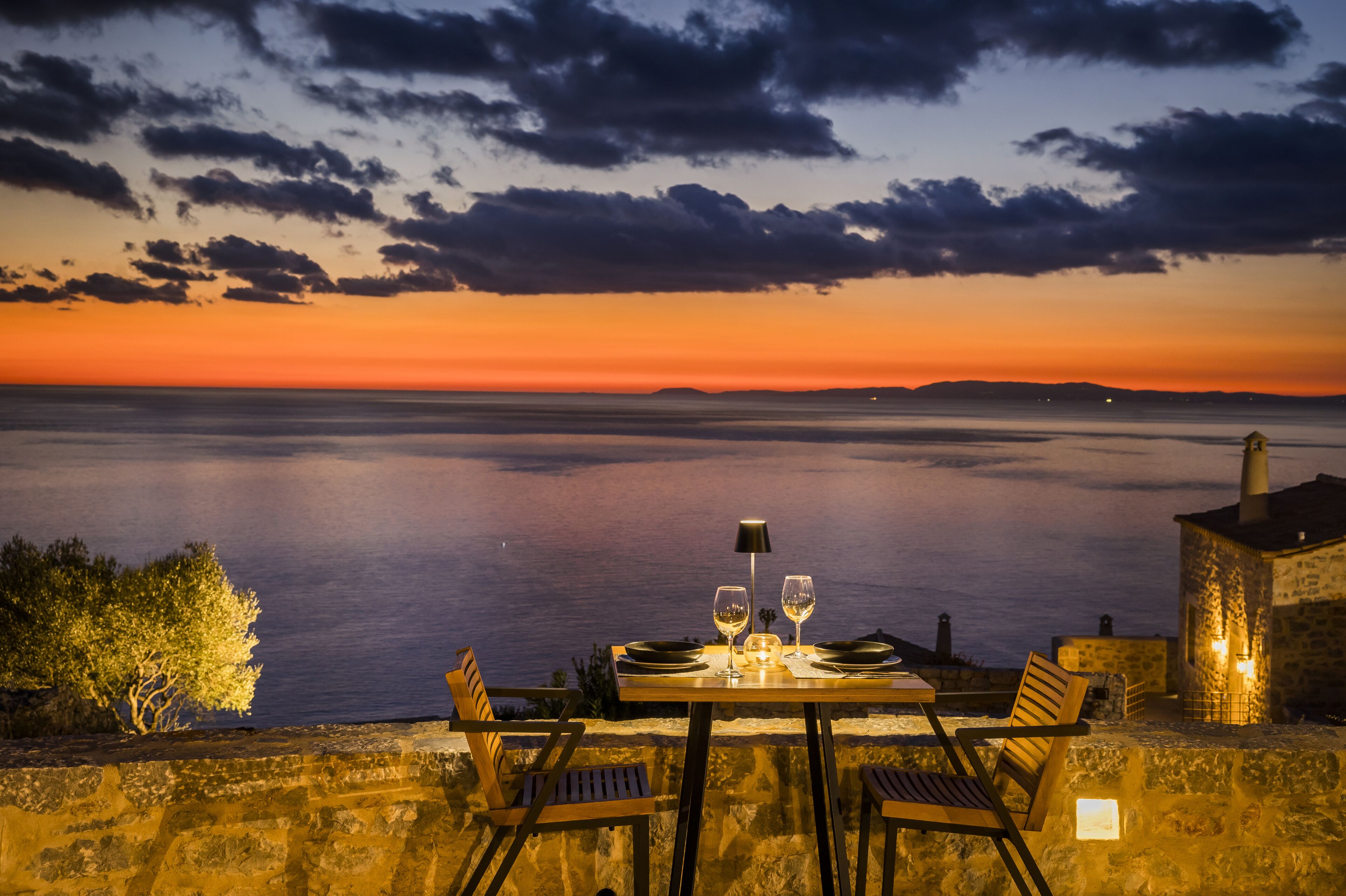 A table set for two with a view of the sea at sunset.