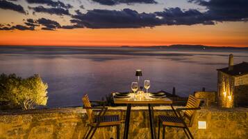 A table set for two with a view of the sea at sunset.