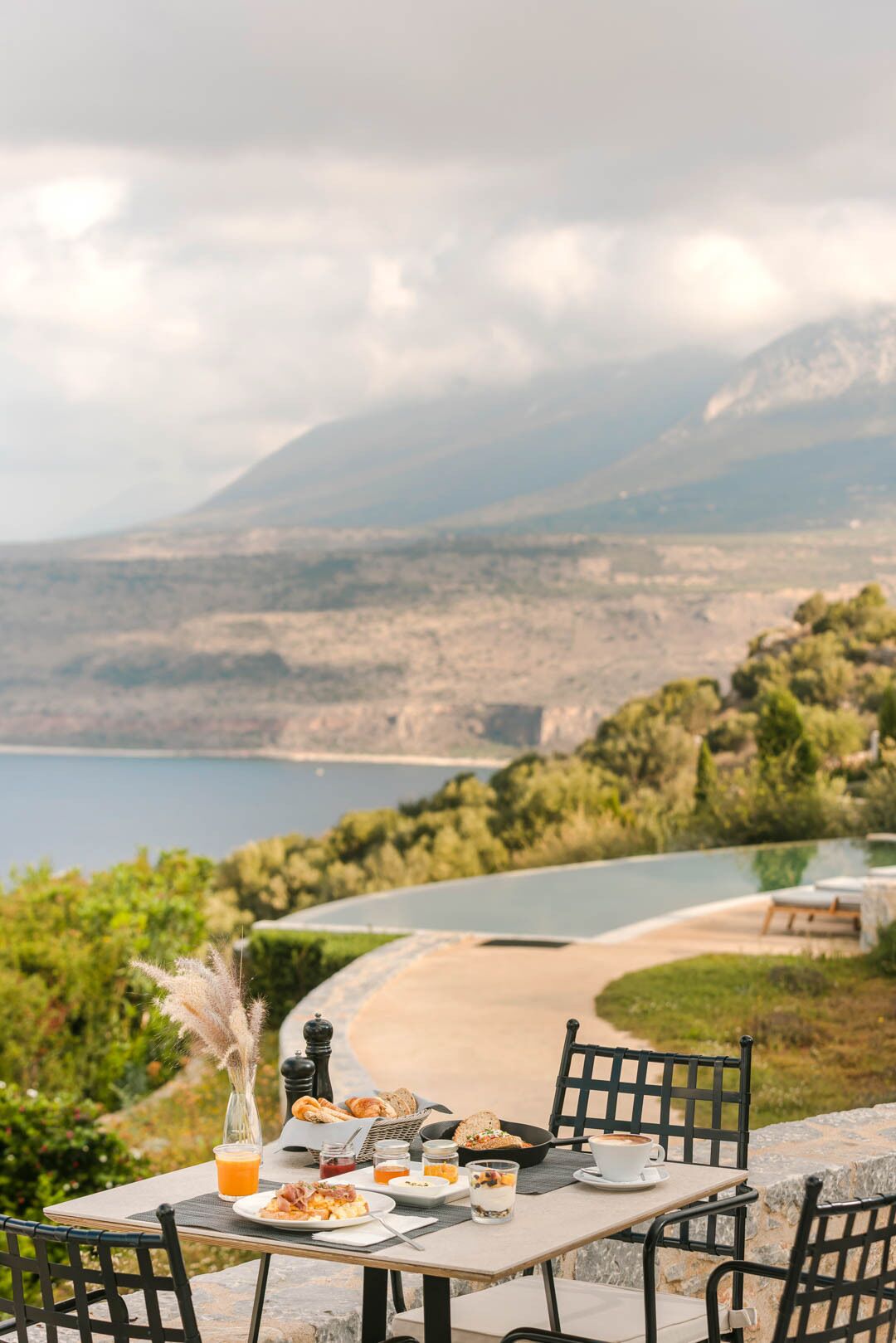 Mesa posta para o café da manhã com vista panorâmica de um lago e montanhas.