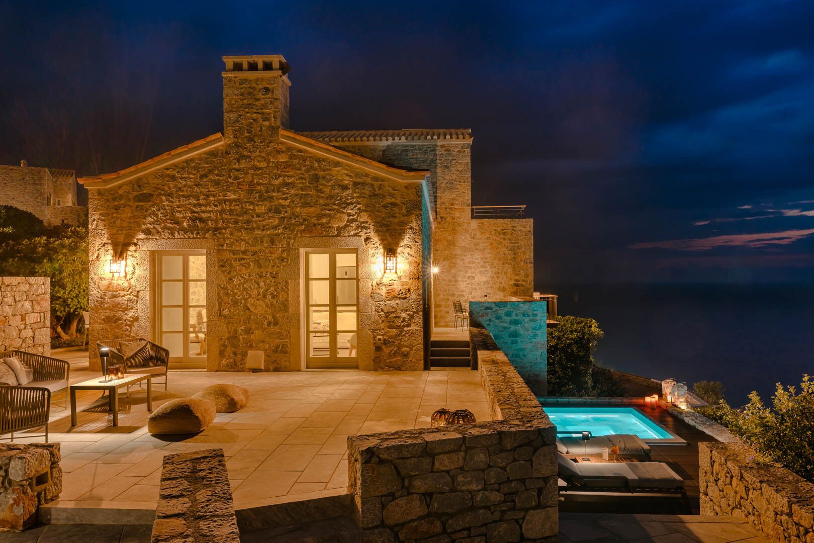 Ein Steinhaus mit Pool, Sitzgelegenheit im Freien und Meerblick.