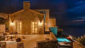 Ein Steinhaus mit Pool, Sitzgelegenheit im Freien und Meerblick.