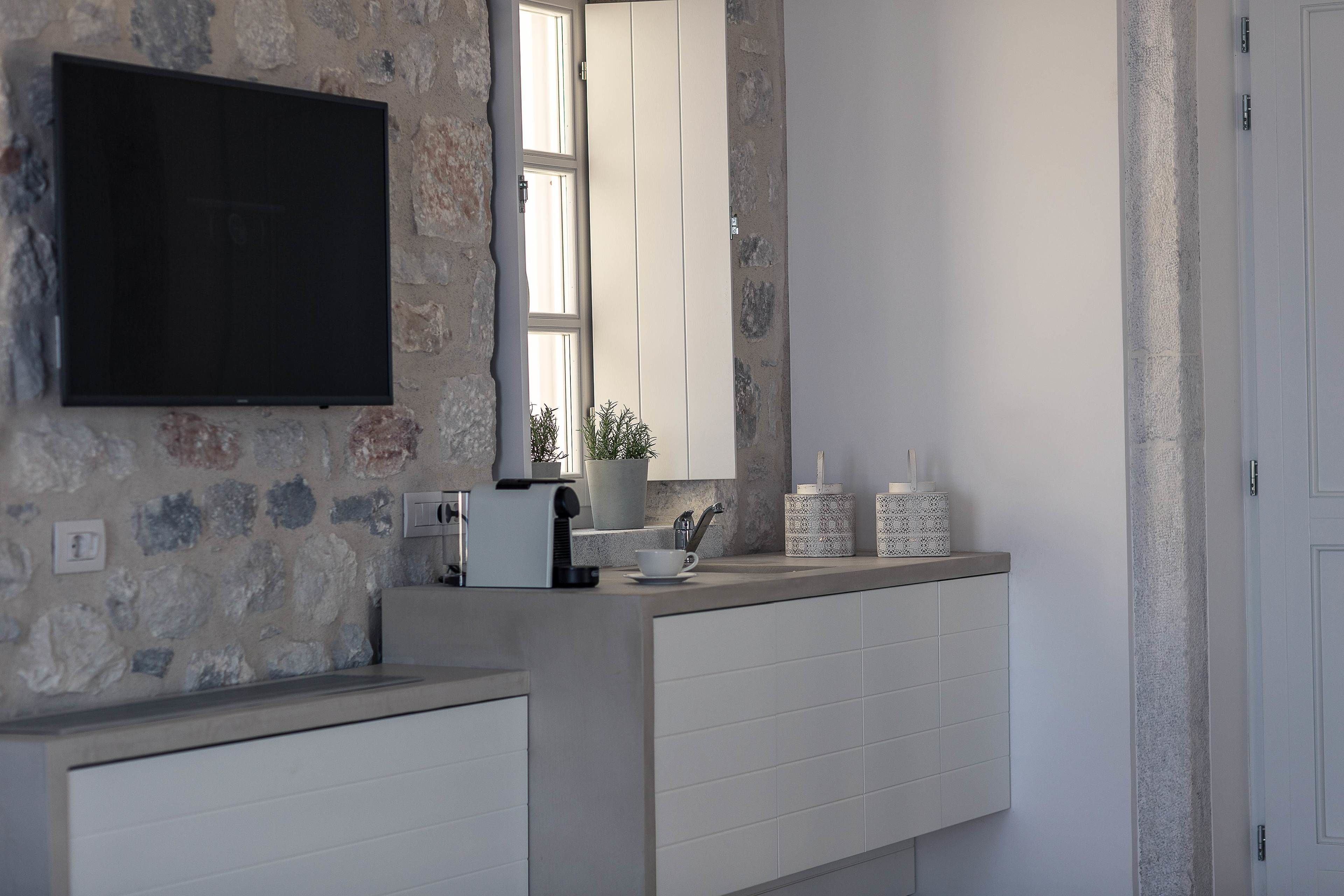 Una cocina moderna con pared de piedra, un televisor de pantalla plana, una ventana y una encimera con utensilios de cocina.
