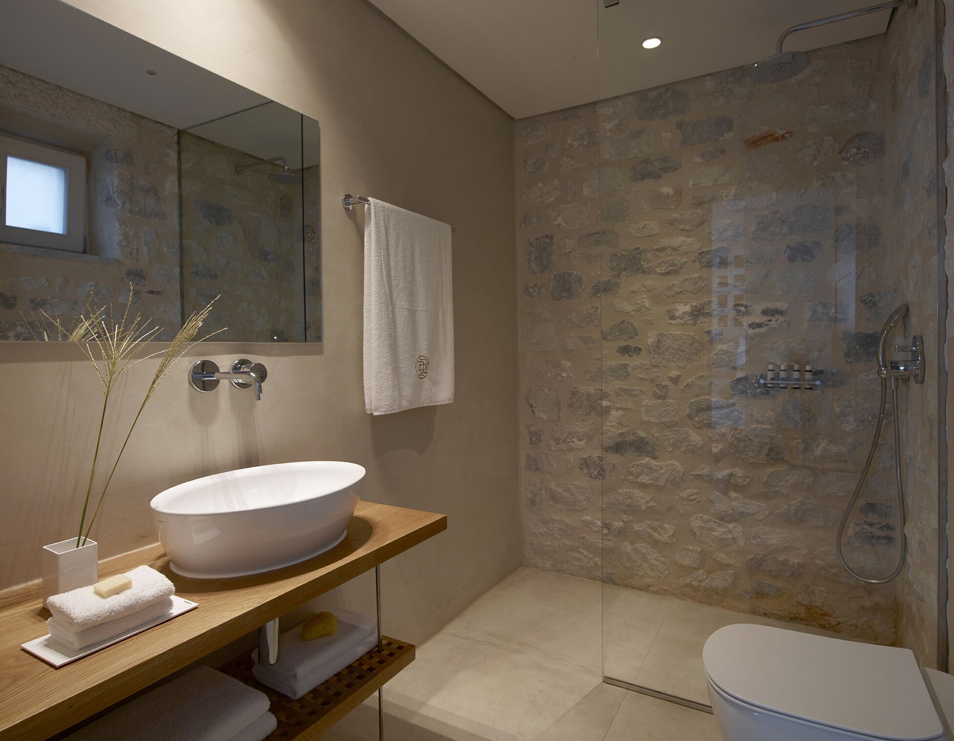 A modern bathroom with a large white sink, a glass-enclosed shower, and a wooden vanity.