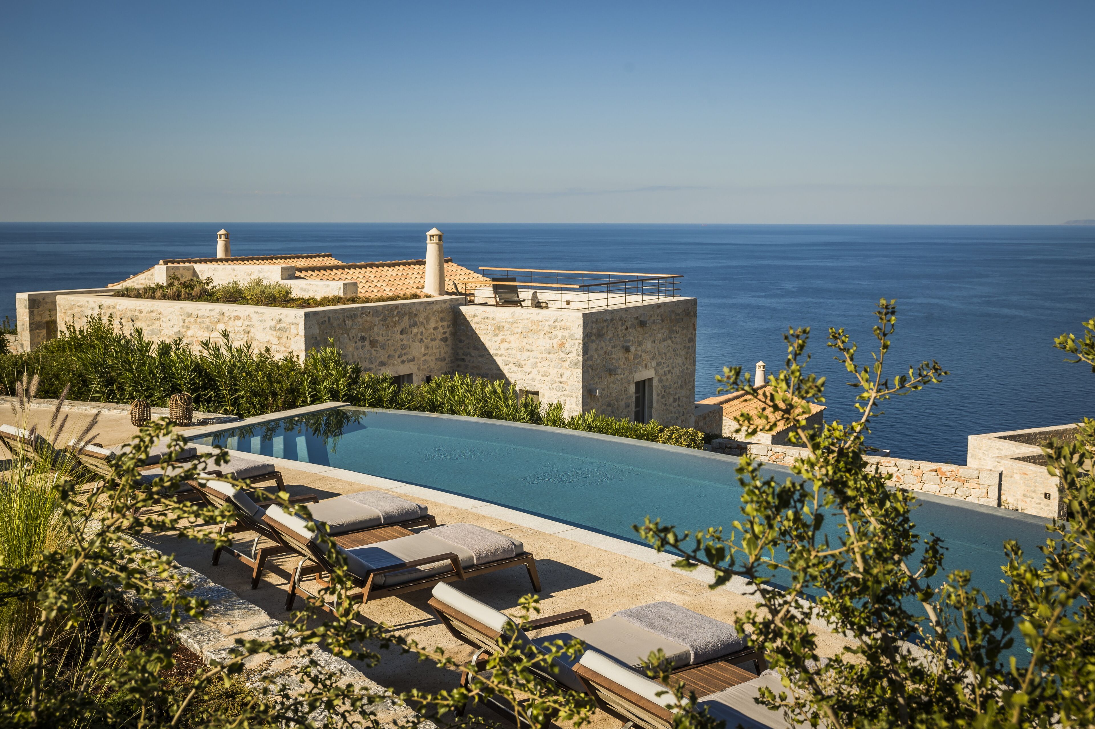 A poolside area with lounge chairs and a view of the sea.