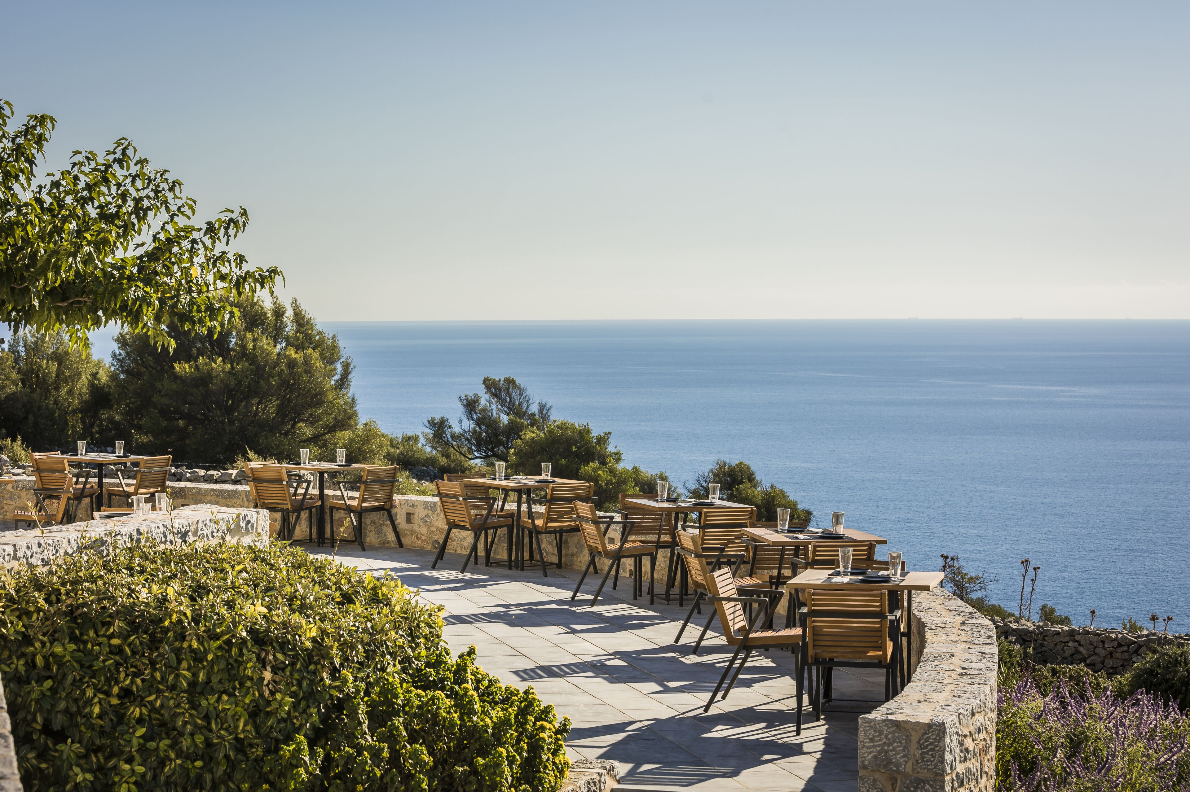An outdoor seating area with tables and chairs overlooking a body of water.