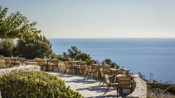 An outdoor seating area with tables and chairs overlooking a body of water.