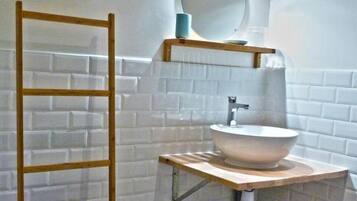 Un baño con una escalera de madera, un lavamanos con espejo y un cubo de basura.
