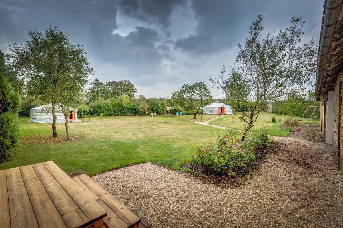 A grassy yard with yurts and a wooden deck.