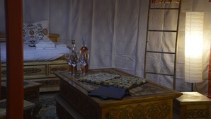Una habitación con una cama, un aparador de madera y una mesa con botellas y vasos.