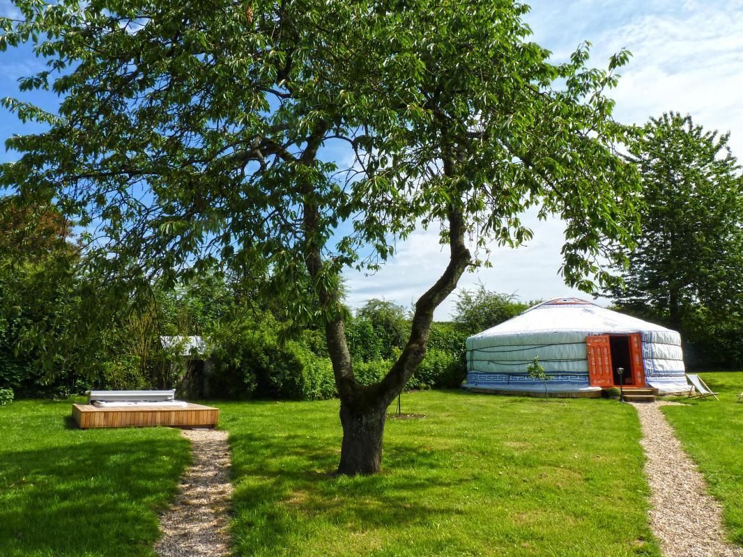 A yurt with a wooden platform and a tree in the foreground.