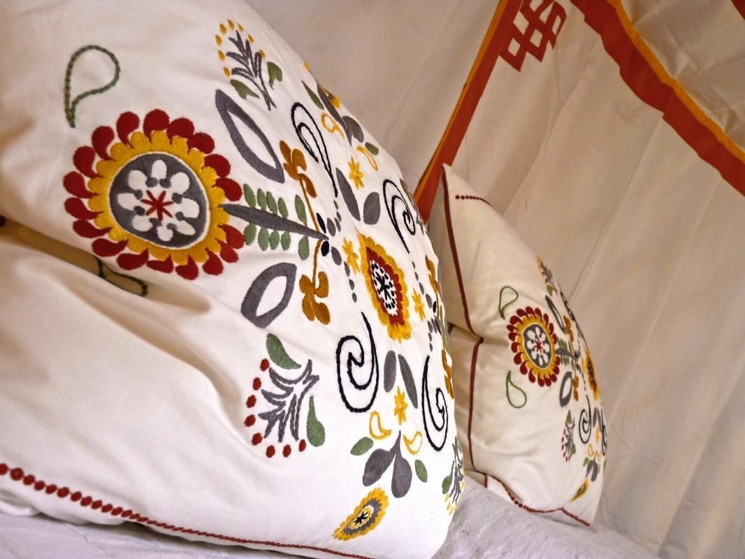 Un lit avec une couette blanche ornée de broderies florales colorées.