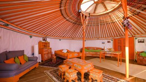 Interior de una yurtas tradicional con sofá, mesa de comedor y sillas.
