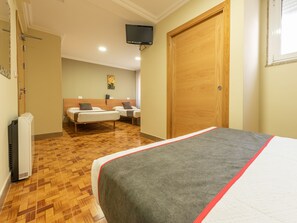 A hotel room with a large bed, two smaller beds, a wooden wardrobe, a television, and a telephone on the wall. - Casa Marín (Sanxenxo)