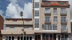 A multi-story hotel with a central tower, balconies, and a storefront for hotel services. - Casa Marín (Sanxenxo)