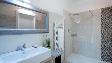 A modern bathroom with a large sink, a glass shower enclosure, and a tiled shower wall.