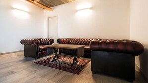 A spacious living room with a large sectional sofa, a coffee table, and a patterned rug. - Agriturismo Camisi (Cambiago)