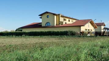 Un edificio ampio, su due piani, con tetto rosso e pareti color crema, immerso in un prato curato.