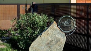 A building with a beige facade, a flat roof, and a large rock in the foreground. - Agriturismo Camisi (Cambiago)