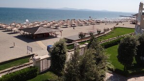A beachside hotel with multiple sun umbrellas and lounge chairs, a pool area, and a view of the sea. - Sunset Resort (Pomorie)