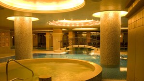 A large indoor swimming pool with a central island, surrounded by columns and a glass bridge. - Sunset Resort (Pomorie)