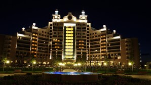 A multi-story hotel with a central atrium, balconies, and a landscaped garden with a fountain. - Sunset Resort (Pomorie)