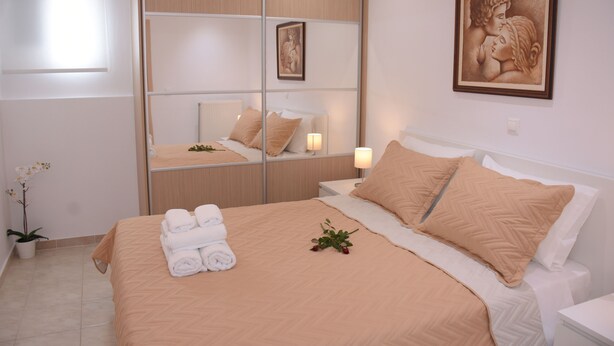 A hotel room with a bed, a mirror, a painting, and a potted plant. - Keratea Apartment Athens Airport (Lavreotiki)