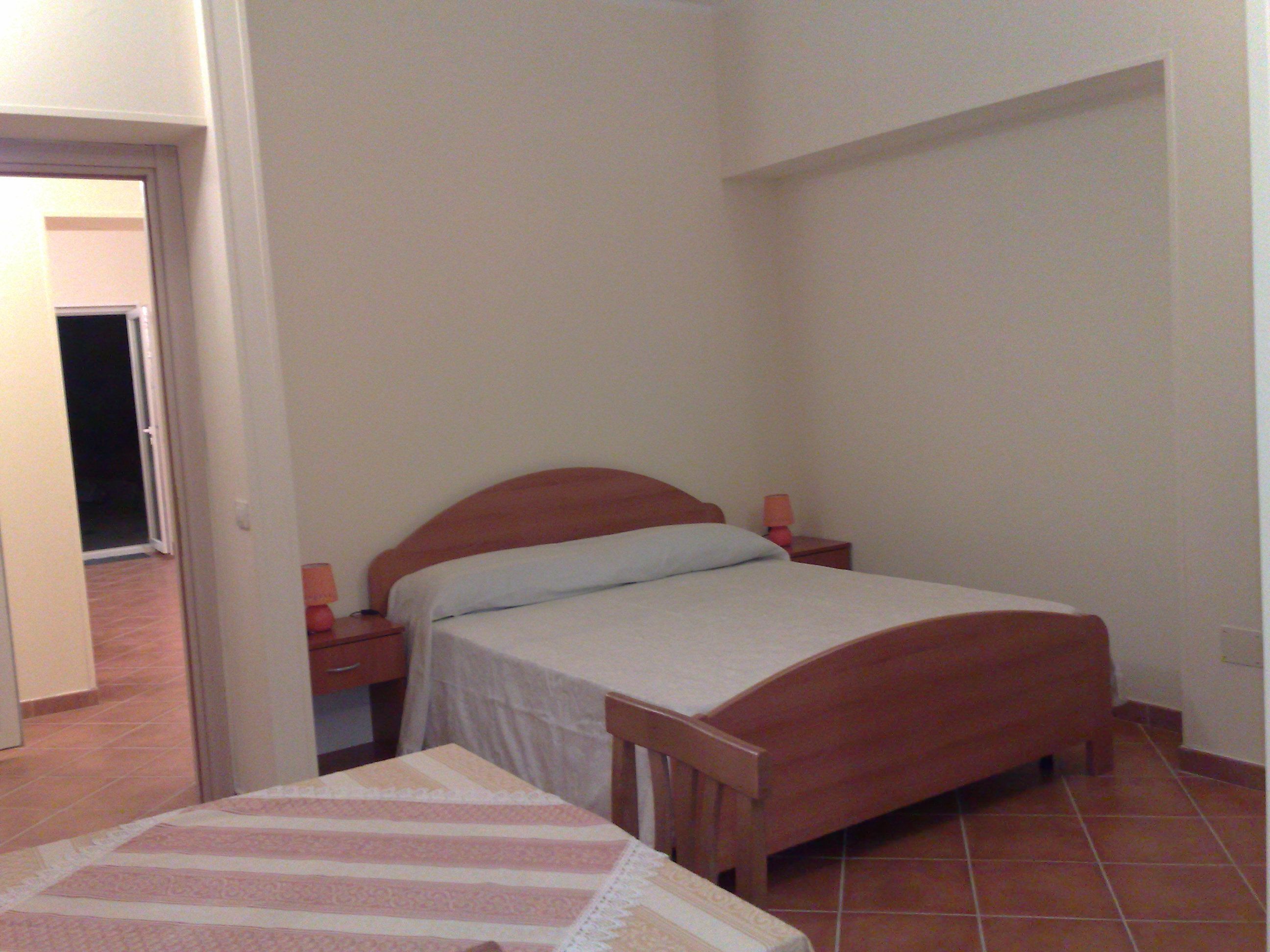 A small bedroom with a single bed, a nightstand, and a bedside table.