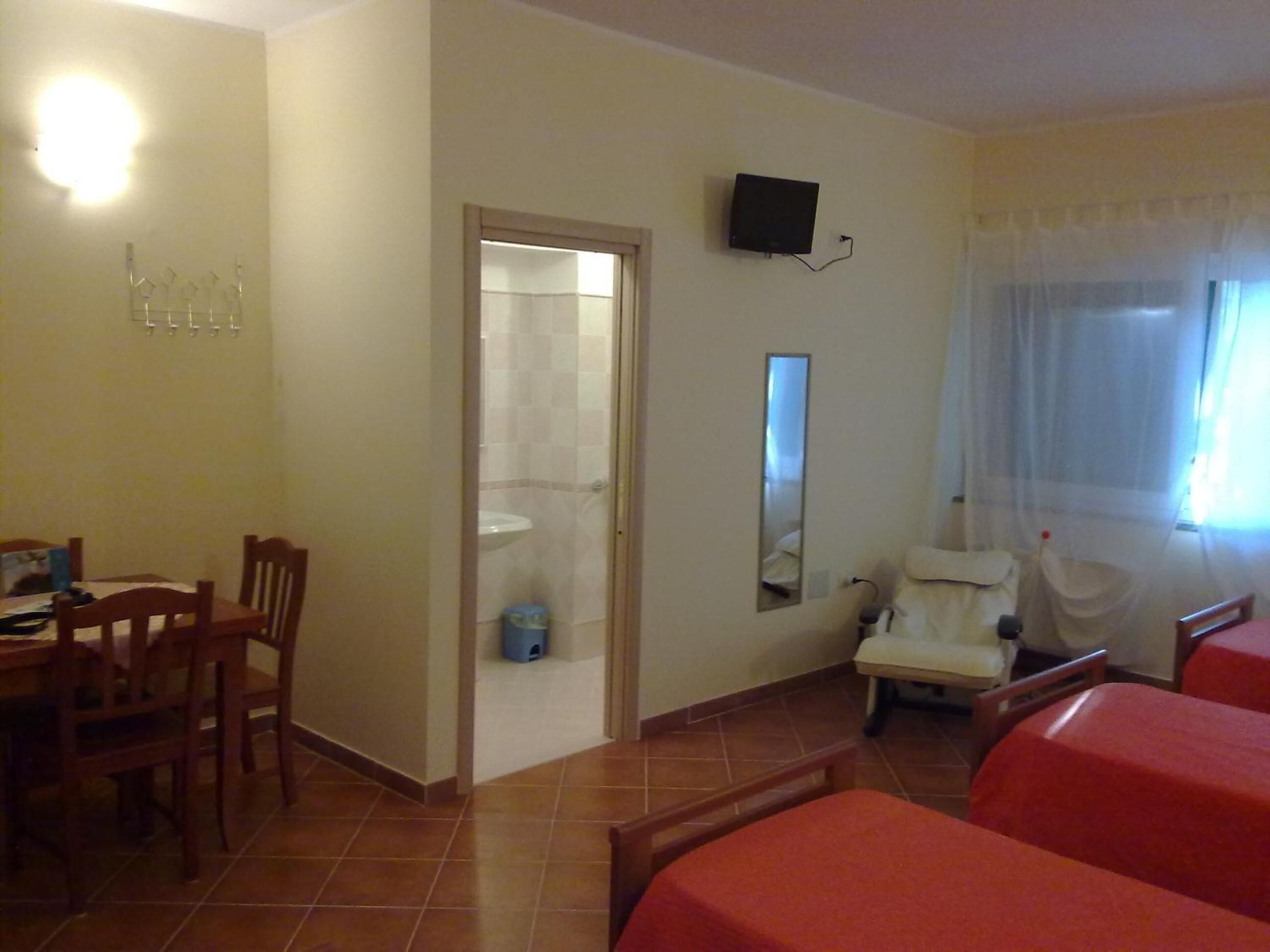 Una habitación de hotel con una cama, una silla, un escritorio y un televisor.
