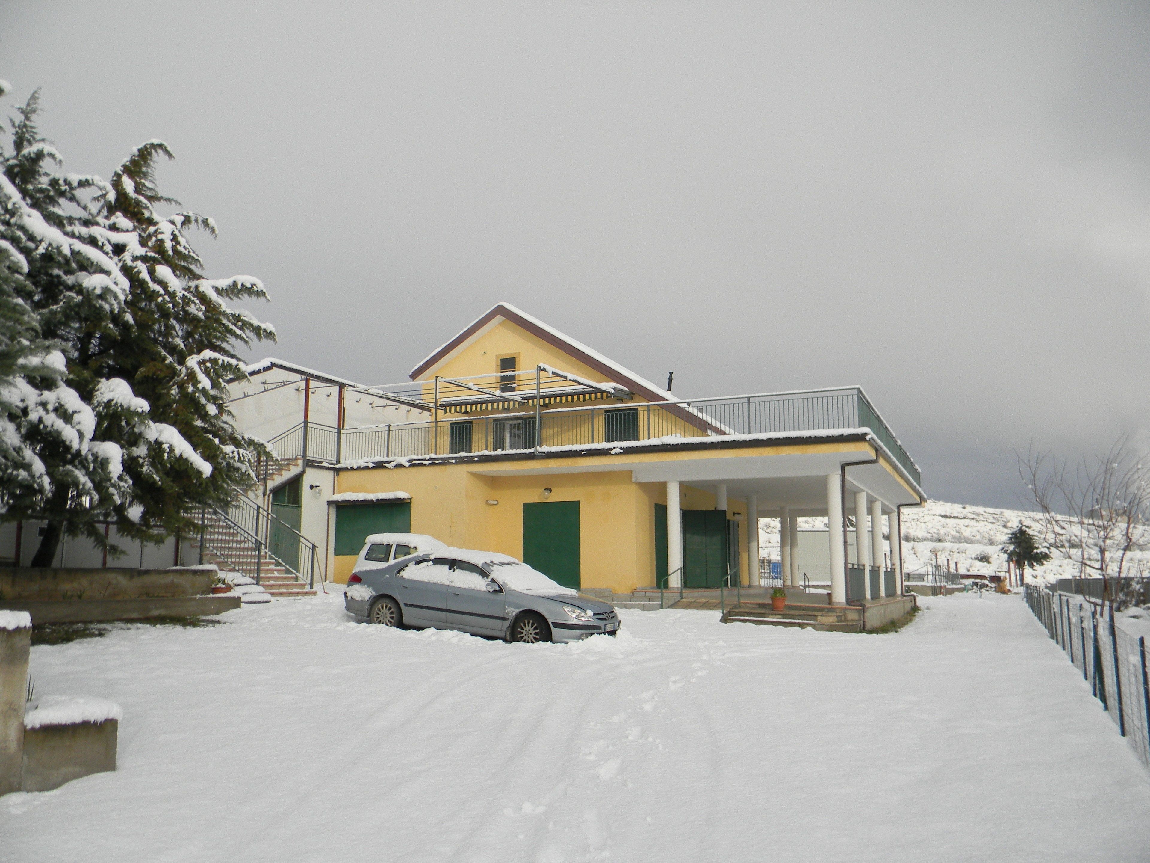 A two-story yellow building with a covered driveway and a car parked in front.