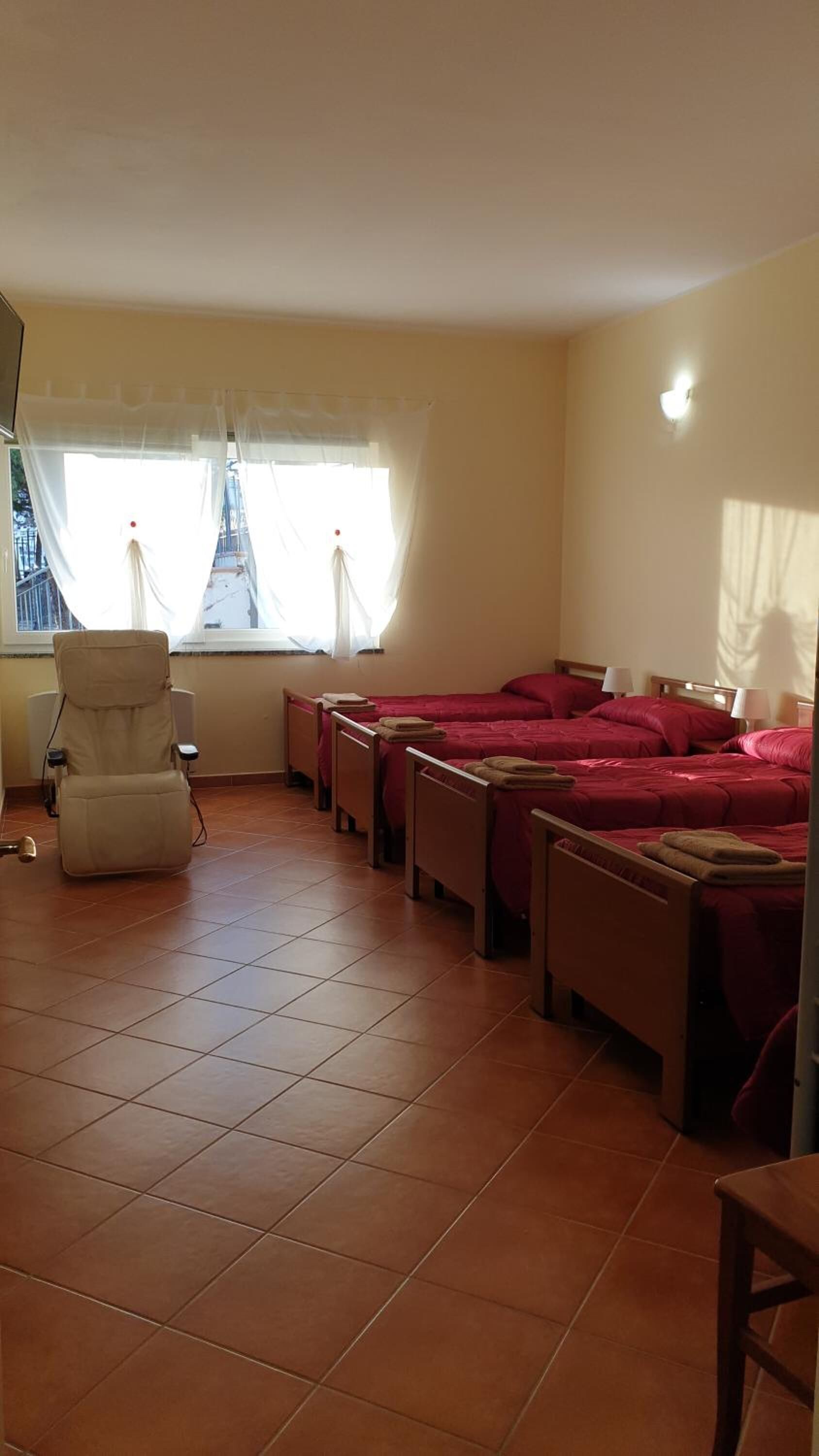 Een hotelkamer met een bed, een stoel en een raam met gordijnen.