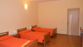 Habitación de hotel con tres camas de madera, cada una con una lámpara blanca a su lado.