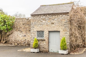 A stone building with a door and window, surrounded by plants and a wall. - Leixlip Manor Hotel (Leixlip)