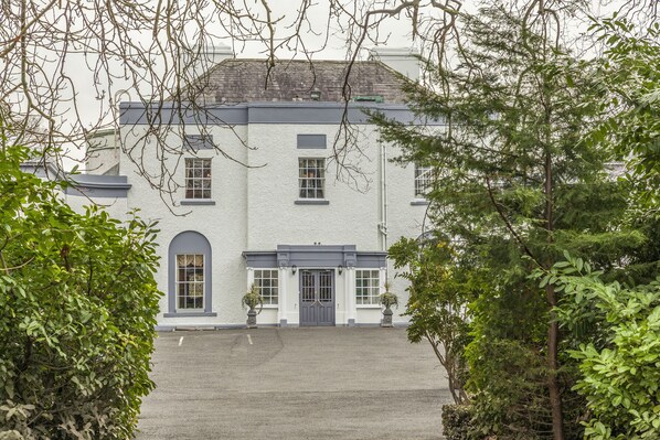 A two-story building with a symmetrical facade, large windows, and a central entrance with a door. - Leixlip Manor Hotel (Leixlip)