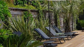 Une terrasse en bois avec des chaises longues et un jacuzzi.