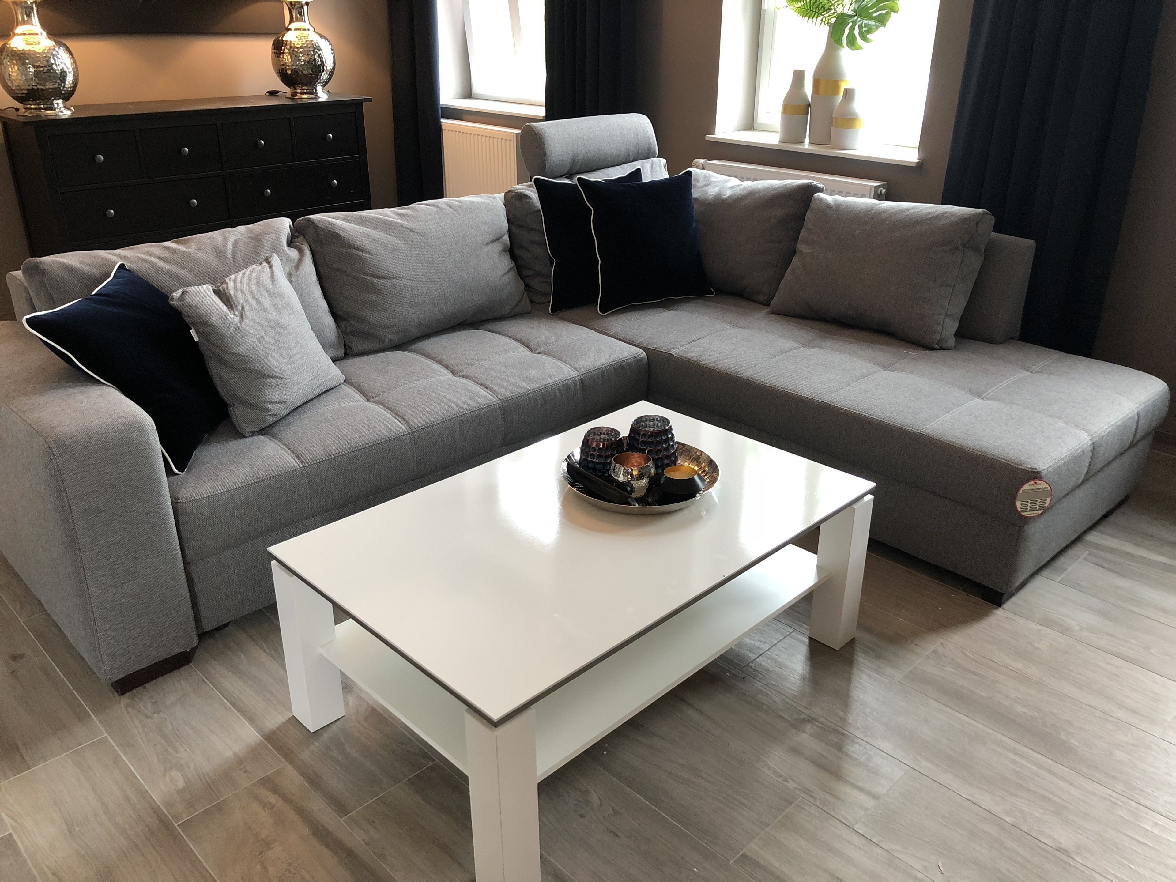 A modern living room with a grey sectional sofa, a white coffee table, and decorative items.
