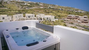 Un jacuzzi en un balcón con vista a un pueblo en la ladera.
