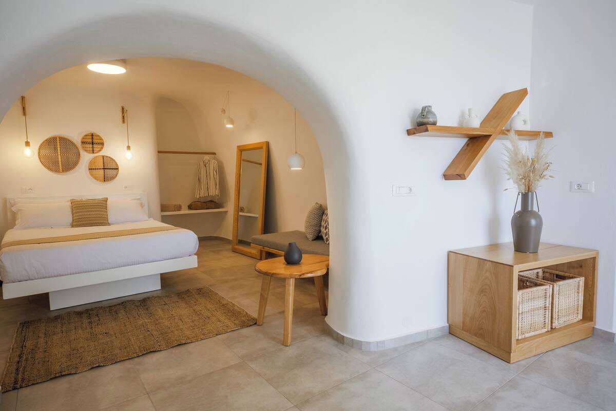 Un dormitorio moderno con cama, mesitas de noche, un espejo y un armario de madera con cestas.