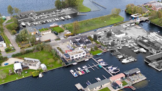 An aerial view of a marina with boats docked, a reception area, and a building with a sloped roof. - Vvp Verhuur Visserslust Vinkeveen (Vinkeveen)