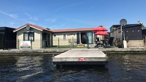 A waterfront property with a dock, a signboard, and a building with a red roof. - Vvp Verhuur Visserslust Vinkeveen (Vinkeveen)